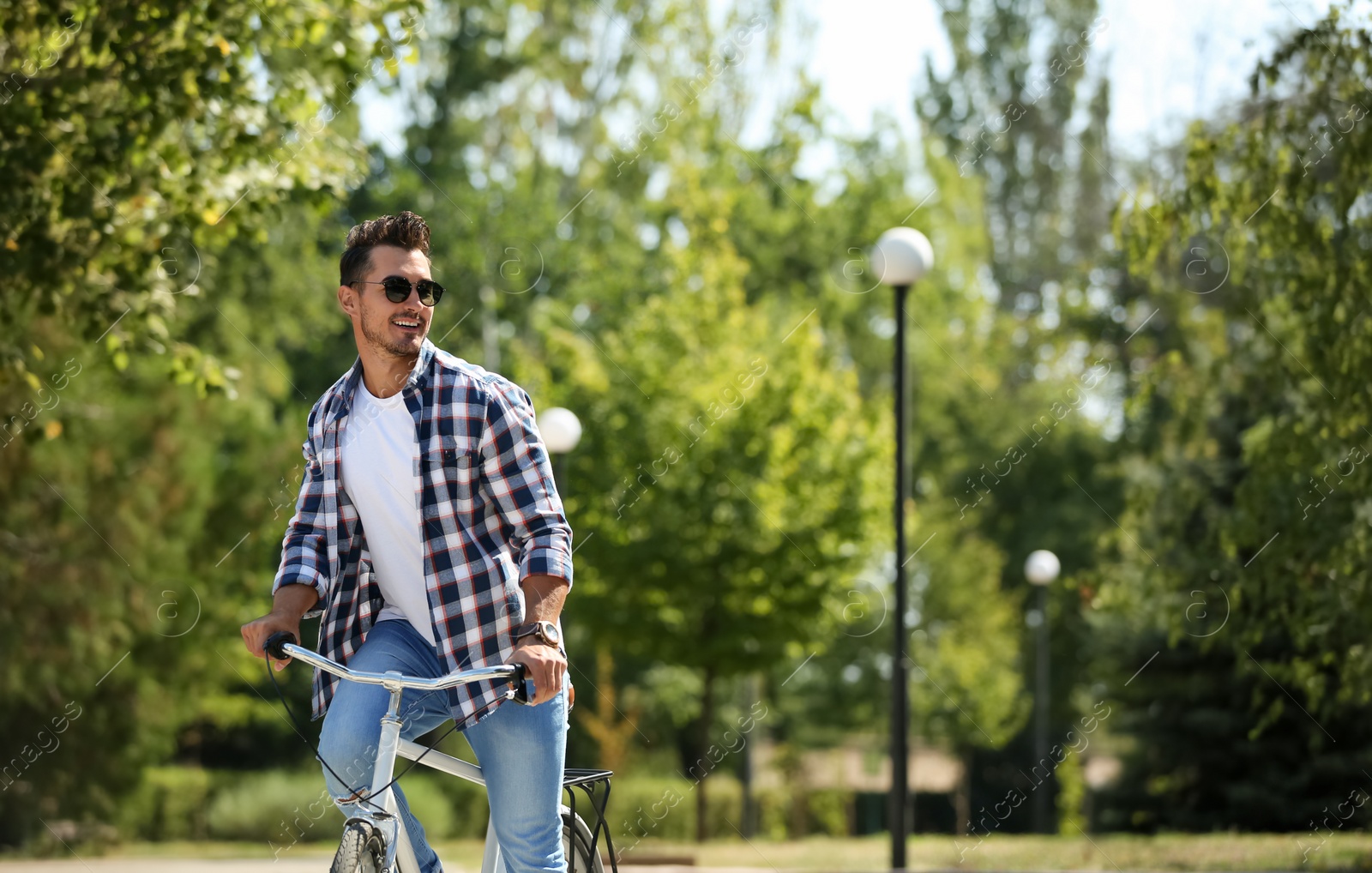 Photo of Handsome young hipster man riding bicycle in park