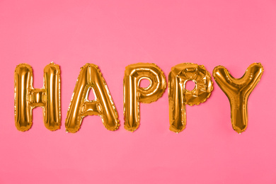 Photo of Word HAPPY made of golden foil balloons letters on pink background