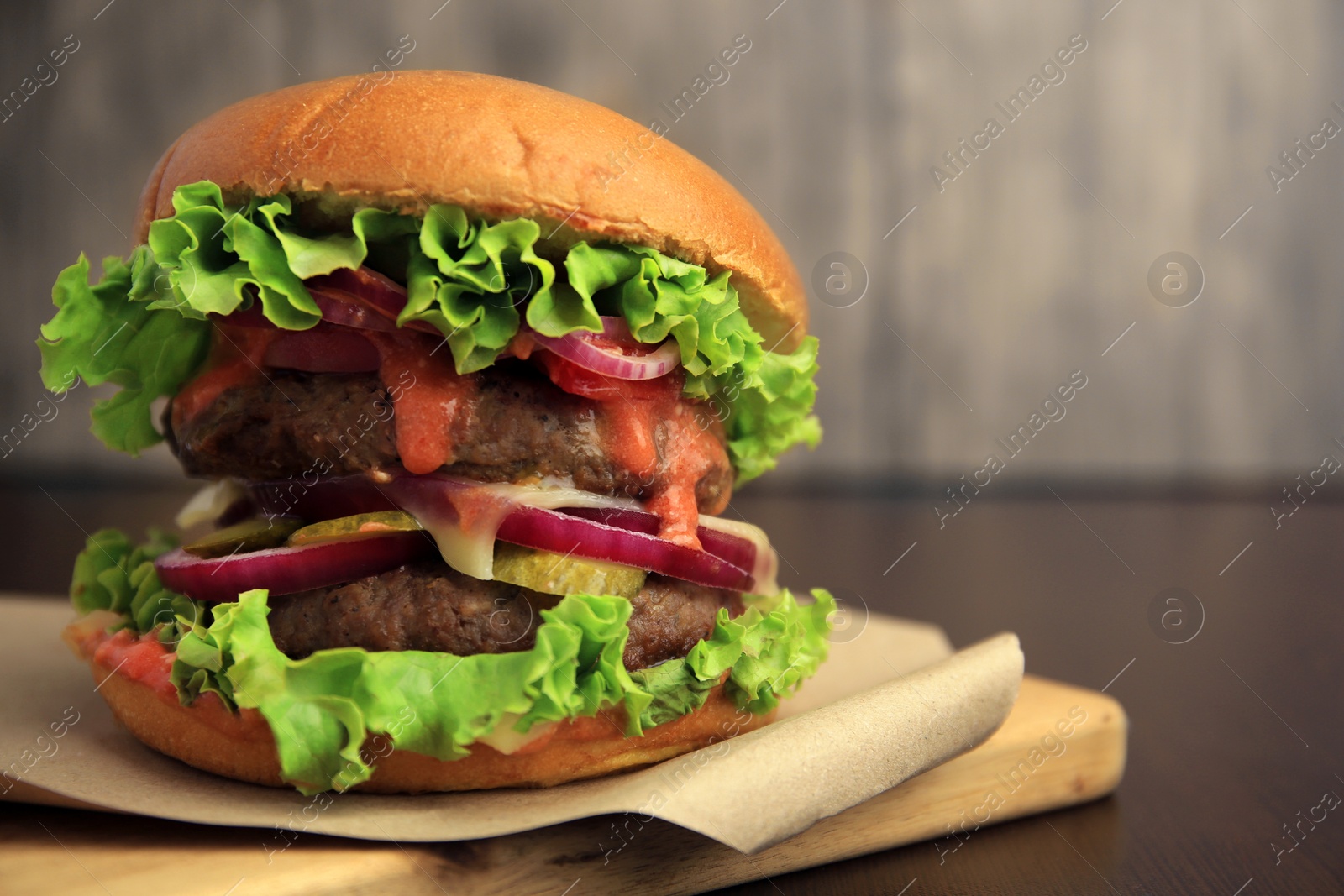 Photo of Board with tasty burger on wooden table, closeup. Space for text