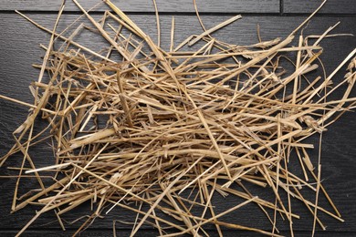 Dried straw on black wooden table, top view. Livestock feed