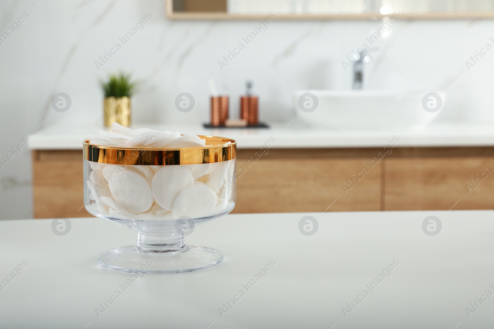 Photo of Jar with cotton pads on table in bathroom