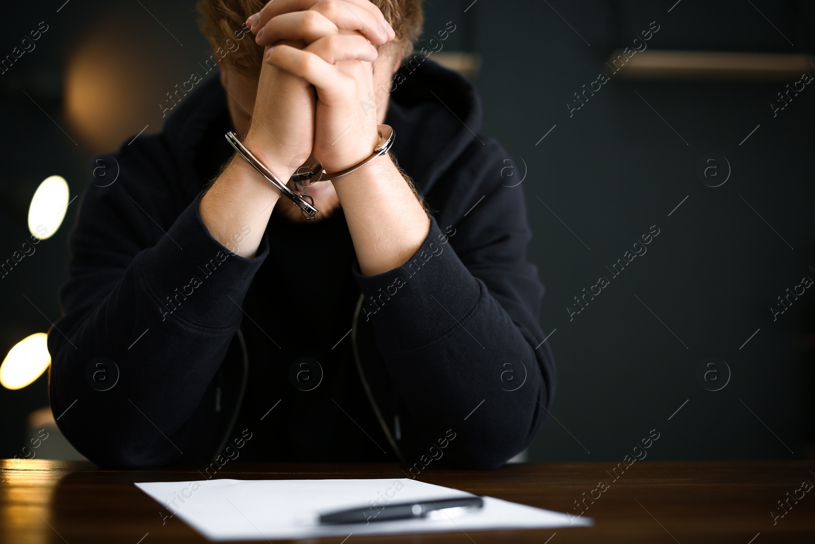 Photo of Criminal in handcuffs with confession at desk indoors. Space for text