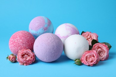 Photo of Colorful bath bombs and beautiful roses on light blue background