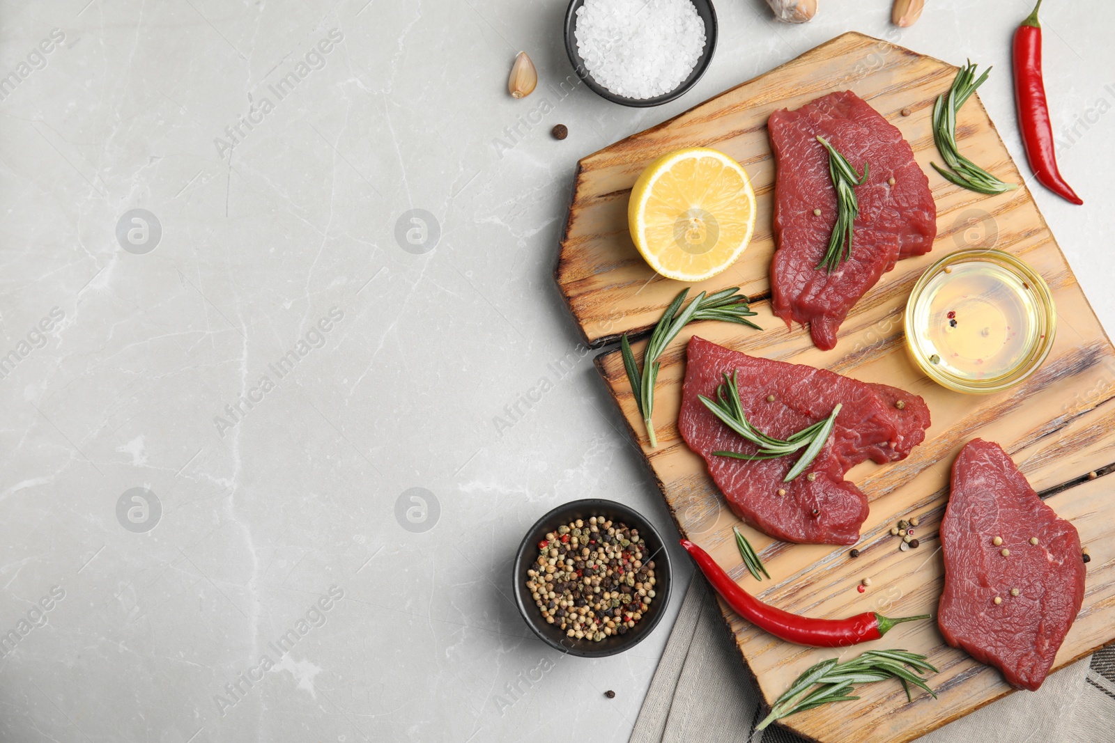 Photo of Fresh raw meat steaks and spices on light grey table, flat lay. Space for text