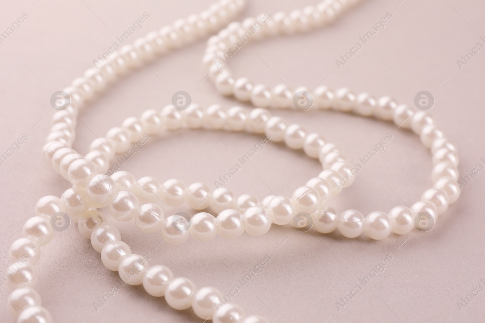 Photo of Elegant pearl necklace on beige background, closeup