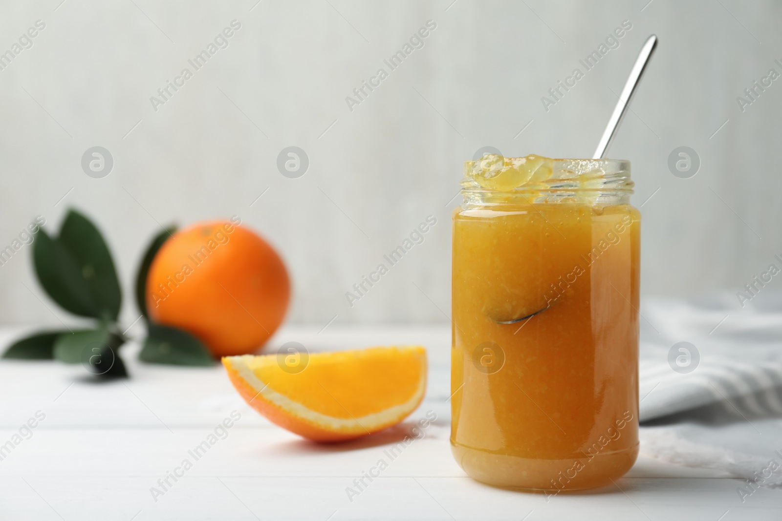 Photo of Delicious orange marmalade in jar on white table, space for text