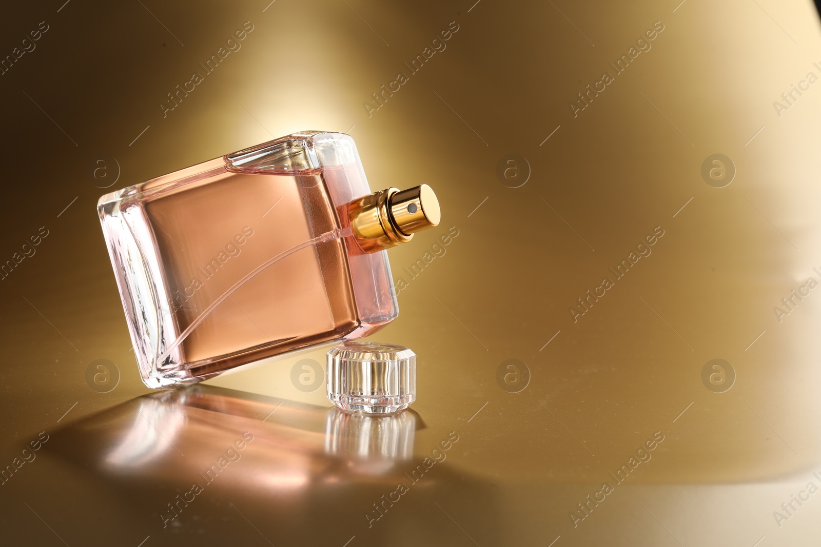 Photo of Luxury women's perfume. Sunlit glass bottle on golden background, space for text