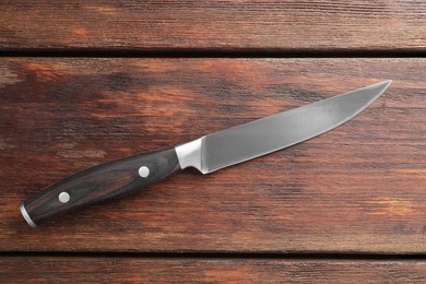 One sharp knife on wooden table, top view