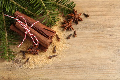 Photo of Different spices and fir branches on wooden table, flat lay. Space for text