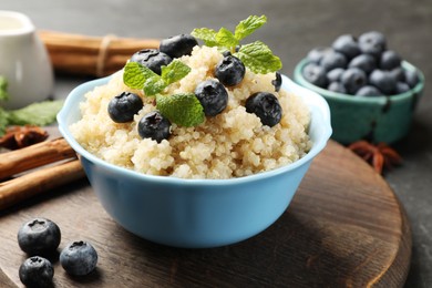 Photo of Tasty quinoa porridge with blueberries and mint in bowl on table, closeup