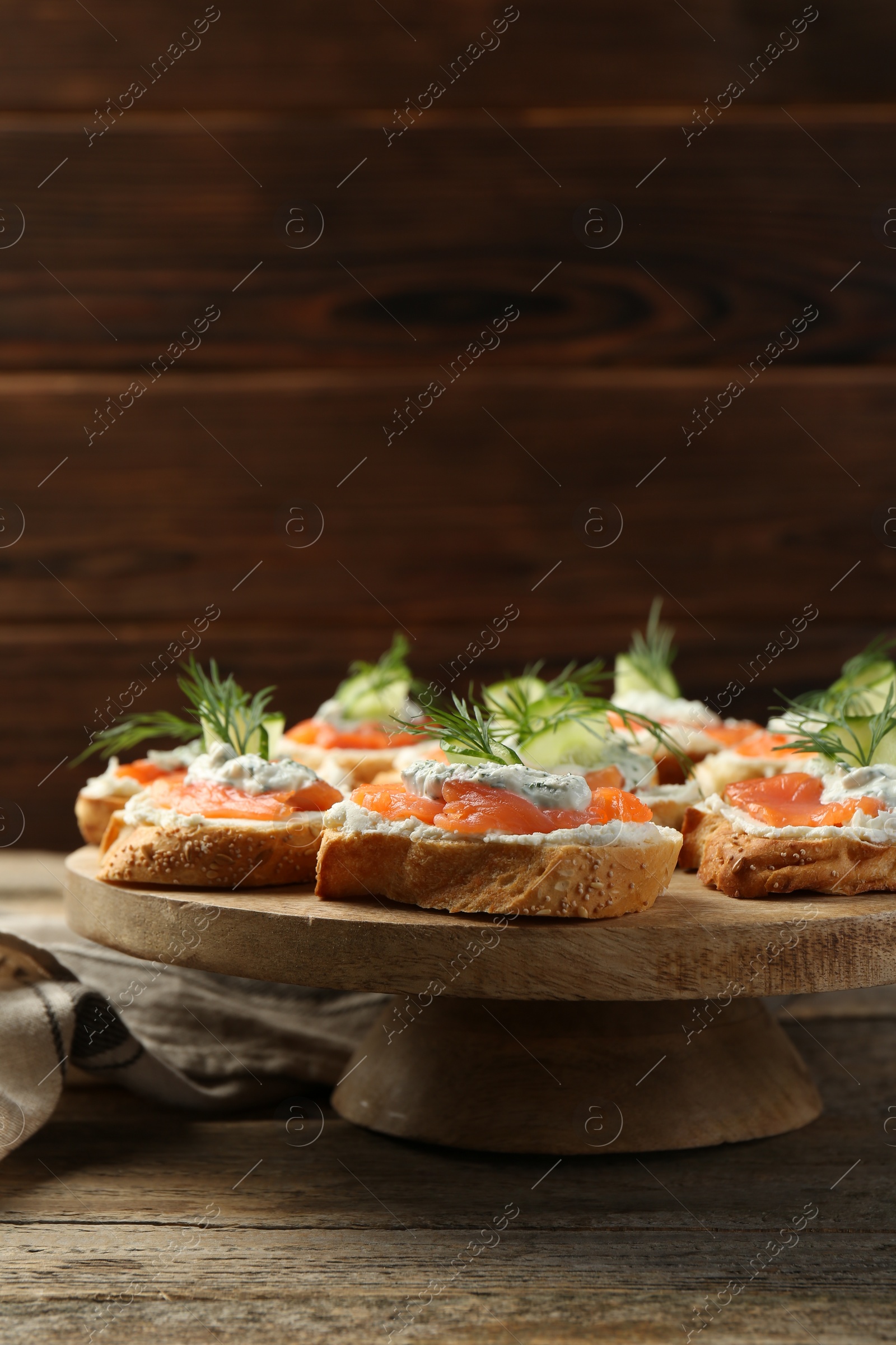 Photo of Tasty canapes with salmon, cucumber, cream cheese and dill on wooden table