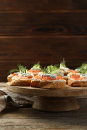 Tasty canapes with salmon, cucumber, cream cheese and dill on wooden table