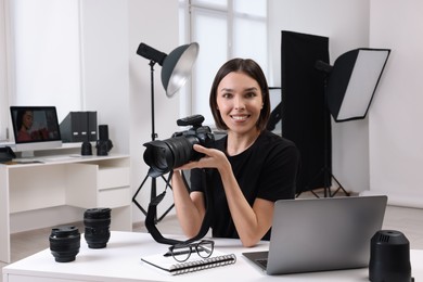 Young professional photographer with camera in modern photo studio