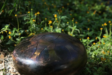 Photo of Steel tongue drum on ground outdoors. Percussion musical instrument