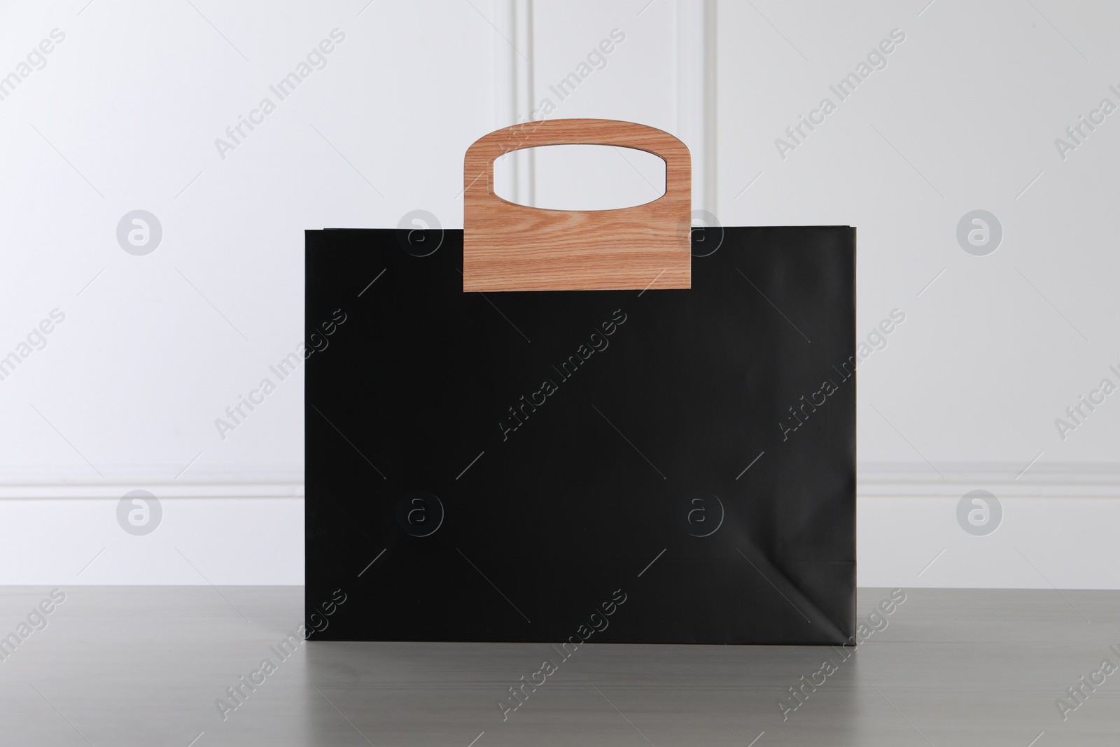 Photo of Black paper bag on white wooden table