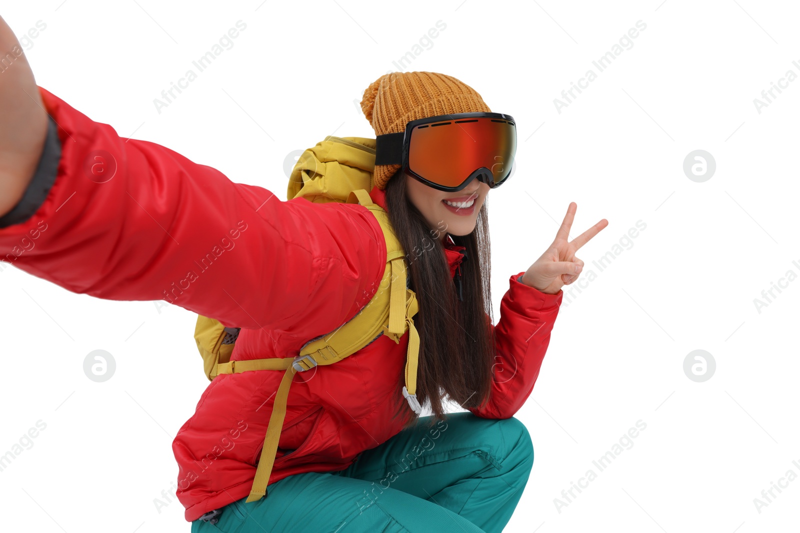 Photo of Smiling woman in ski goggles taking selfie and showing peace sign on white background