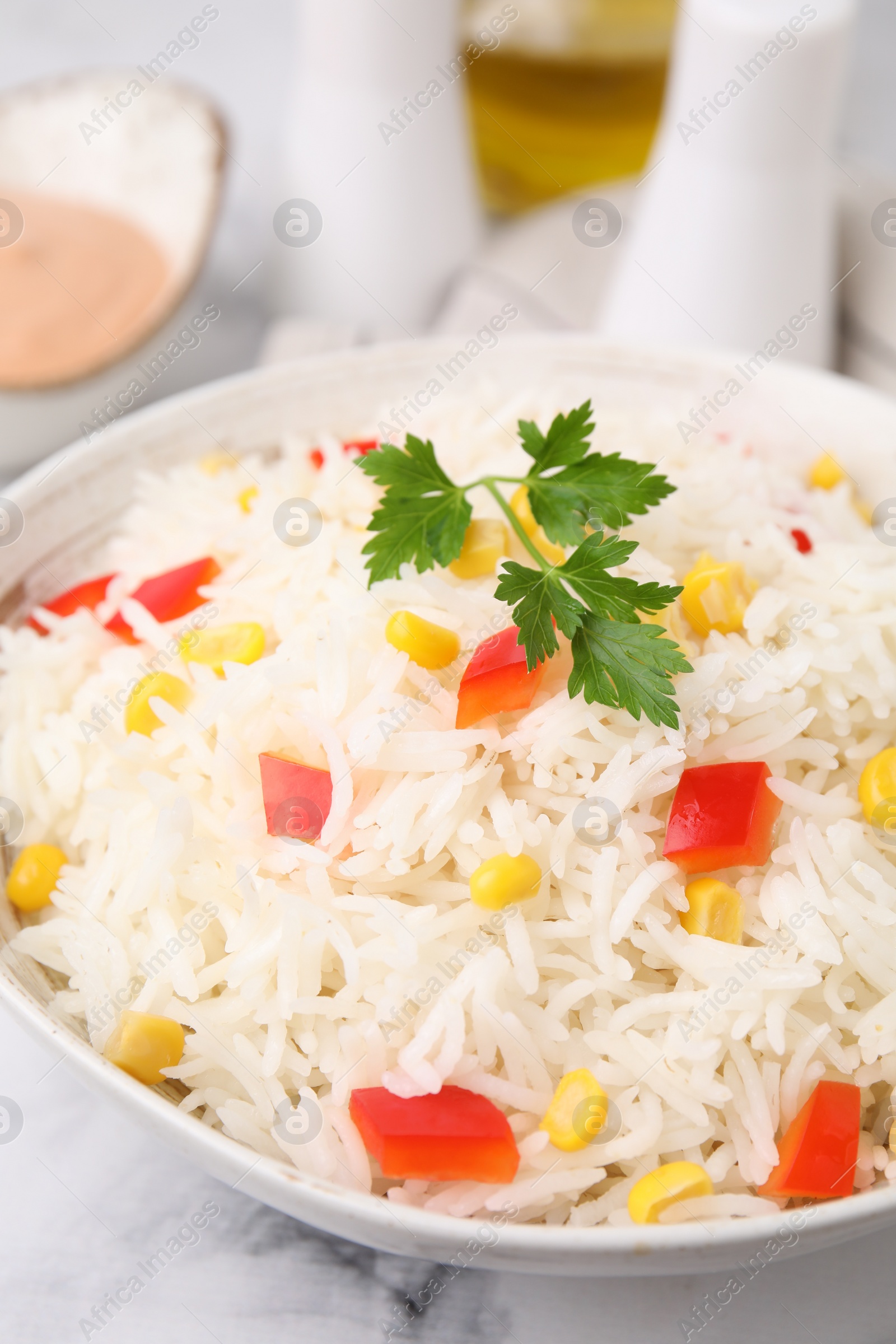 Photo of Bowl of delicious rice with vegetables and parsley on table, closeup