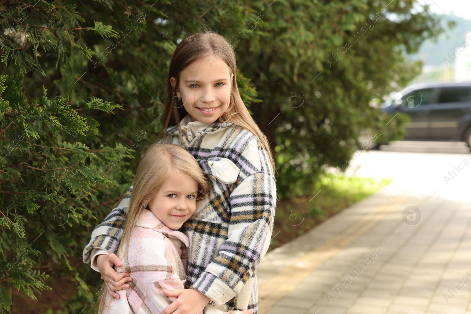 Photo of Cute little sisters spending time together outdoors, space for text