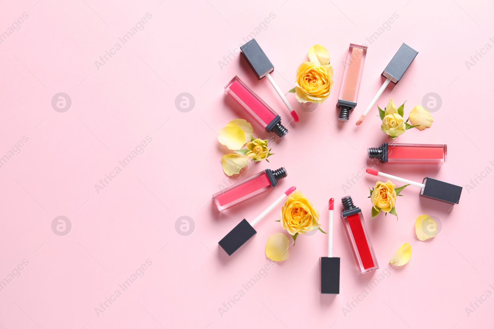 Photo of Composition of lipsticks with flowers on color background, flat lay. Space for text.