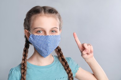 Photo of Girl wearing protective mask on grey background. Child's safety from virus