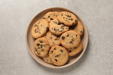 Photo of Plate with delicious chocolate chip cookies on grey table, top view