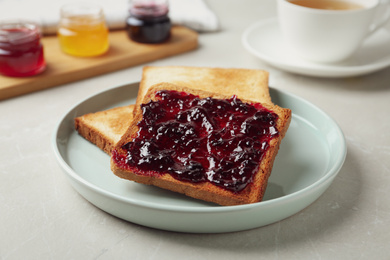 Photo of Delicious crispy toasts with jam on table