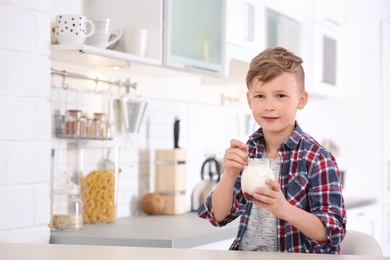 Little boy with yogurt in kitchen