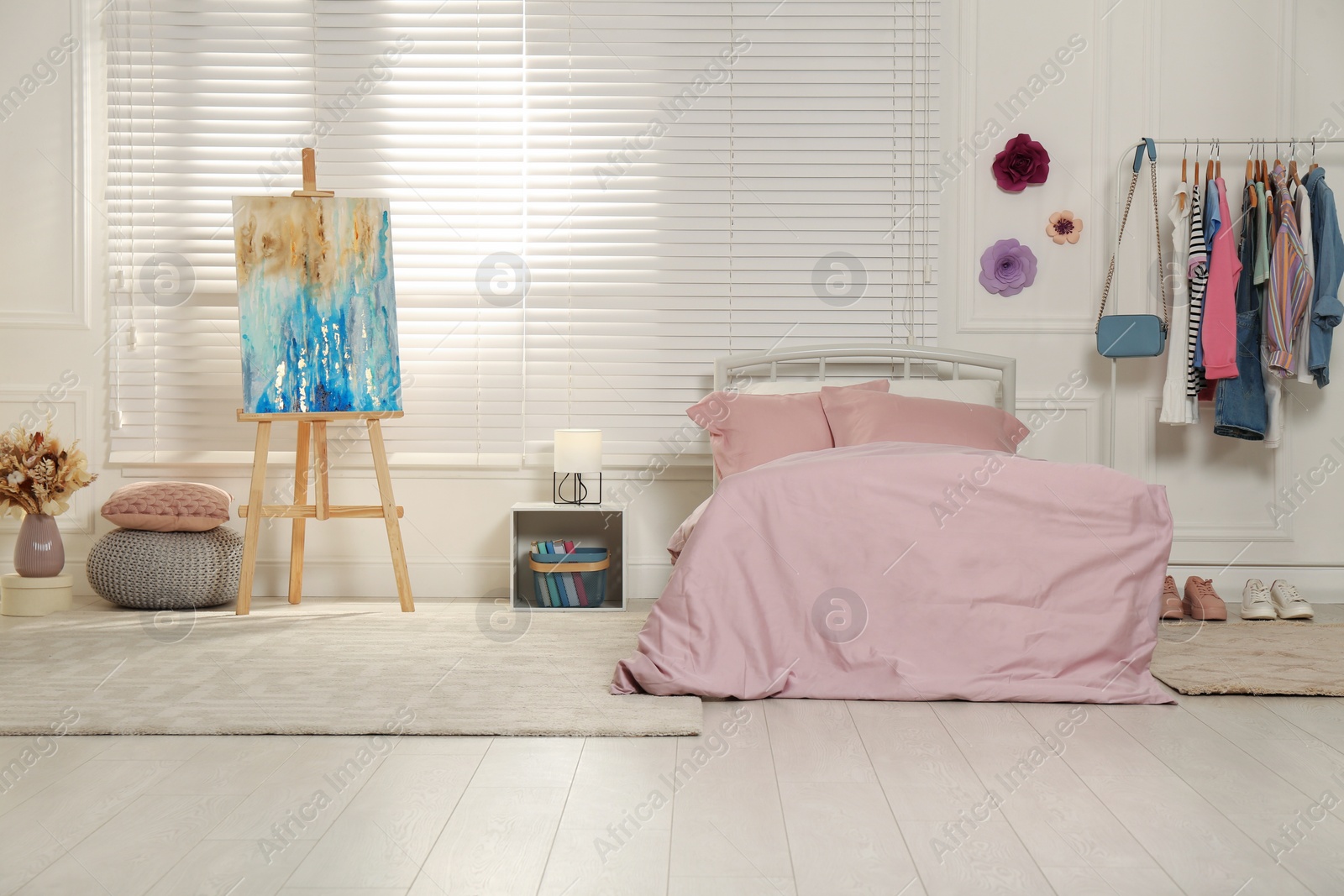 Photo of Stylish teenager's room interior with comfortable bed and painting easel