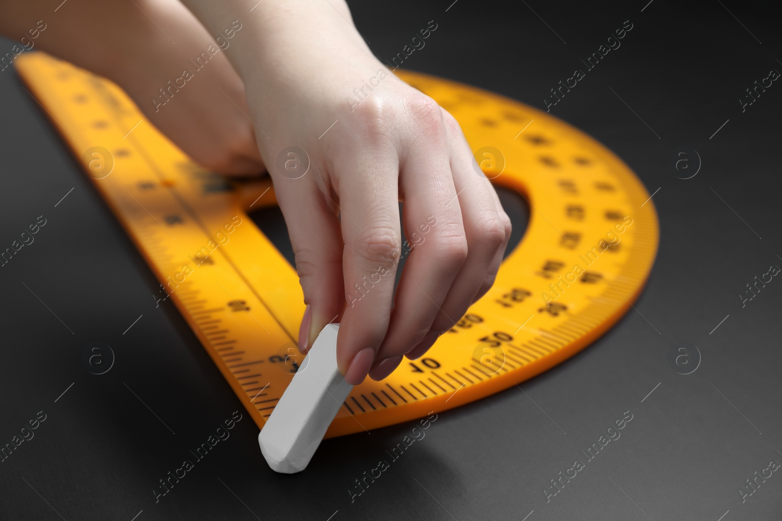 Photo of Woman drawing with chalk and protractor on blackboard, closeup