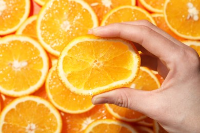 Photo of Woman squeezing juicy orange near slices of fruit, top view