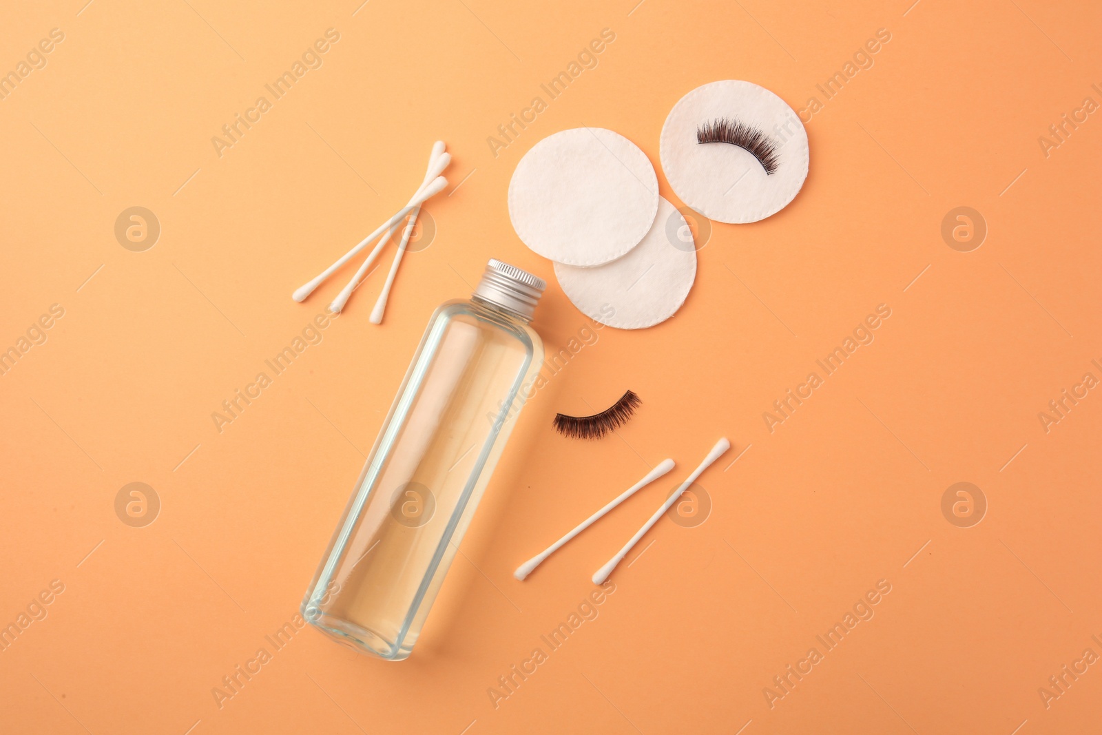 Photo of Flat lay composition with makeup remover and false eyelashes on pale orange background