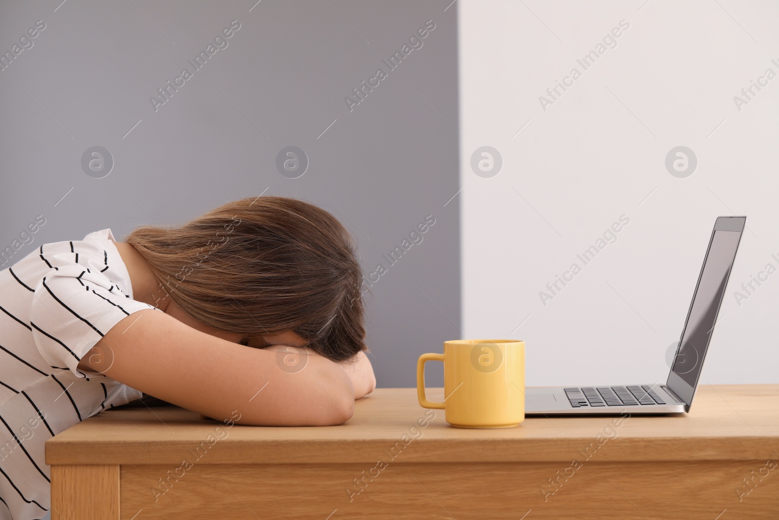 Photo of Woman sleeping in front of laptop at wooden table indoors