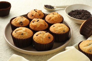 Photo of Delicious sweet muffins with chocolate chips on light textured table