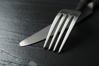 Stylish cutlery. Fork and knife on black table, closeup