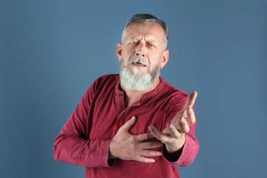 Photo of Mature man having heart attack on color background