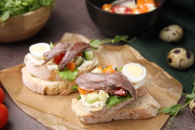 Delicious bruschettas with anchovies, eggs, cream cheese, tomatoes, bell peppers and cucumbers on grey table