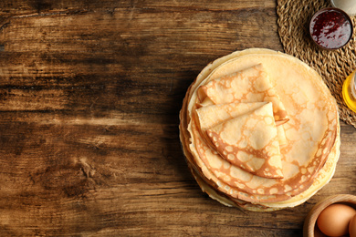 Photo of Flat lay composition with fresh thin pancakes on wooden table. Space for text