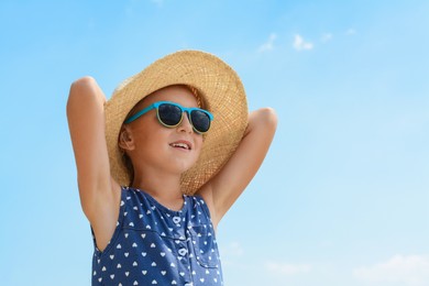 Little girl wearing sunglasses and hat at beach on sunny day. Space for text
