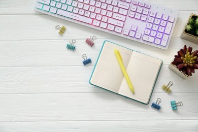 Flat lay composition with modern RGB keyboard on white wooden table, space for text