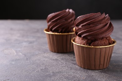 Photo of Delicious chocolate cupcakes on grey textured table, closeup. Space for text