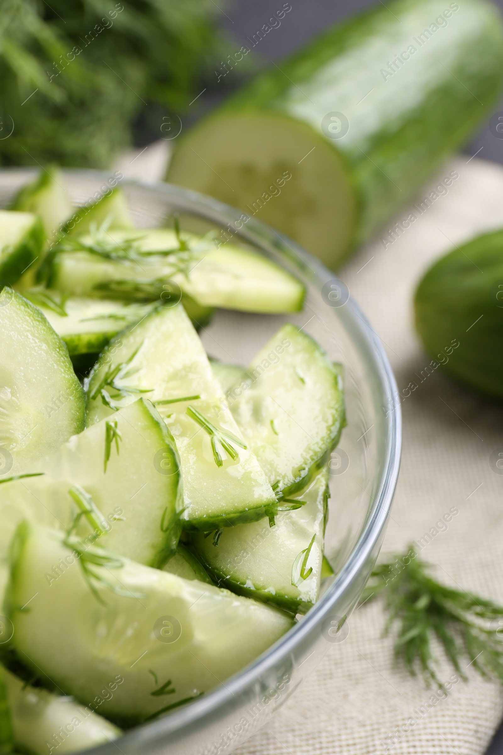 Photo of Cut cucumber with dill in glass bowl on table, closeup