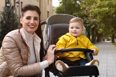 Happy mother with her son in stroller outdoors