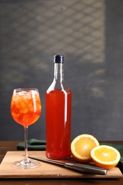 Photo of Aperol spritz cocktail and ice cubes in glass and bottle on wooden table