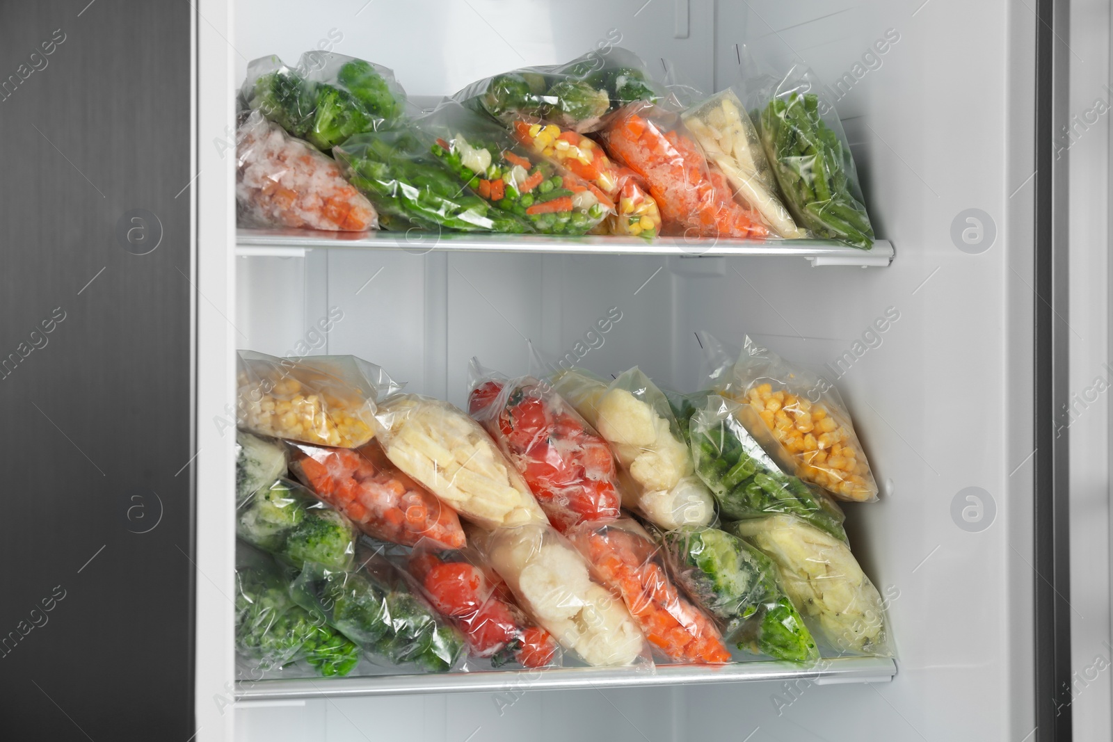 Photo of Plastic bags with different frozen vegetables in refrigerator