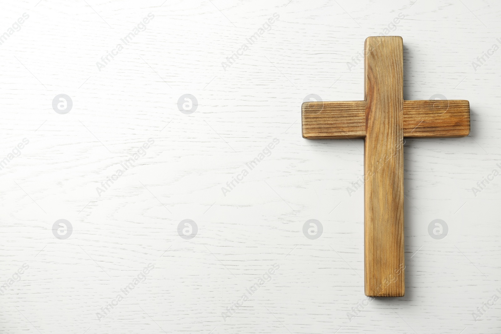 Photo of Christian cross on white wooden background, top view with space for text. Religion concept