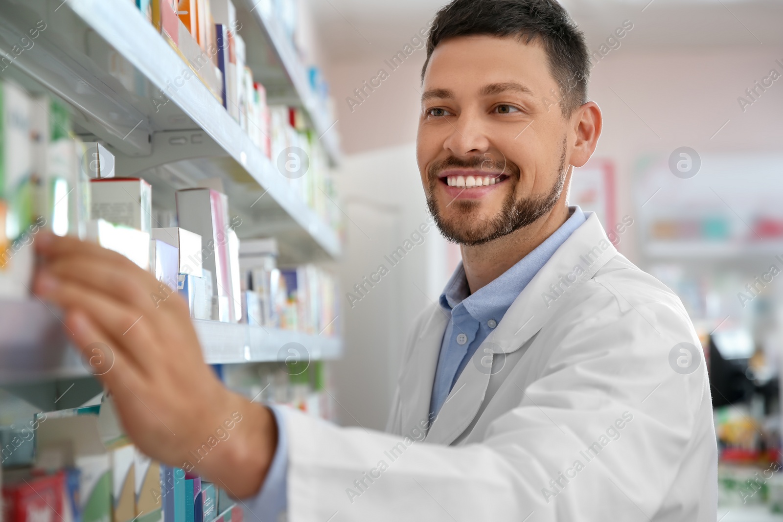 Photo of Professional pharmacist near shelves with merchandise in drugstore