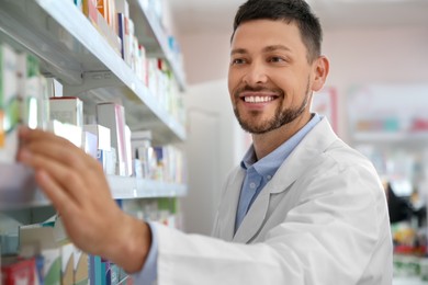 Professional pharmacist near shelves with merchandise in drugstore