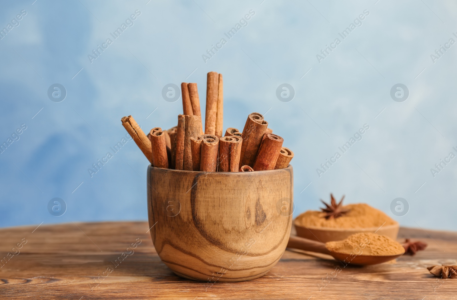 Photo of Bowl with aromatic cinnamon sticks on wooden table