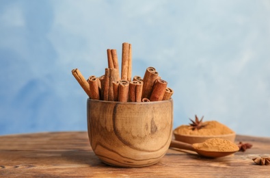 Photo of Bowl with aromatic cinnamon sticks on wooden table