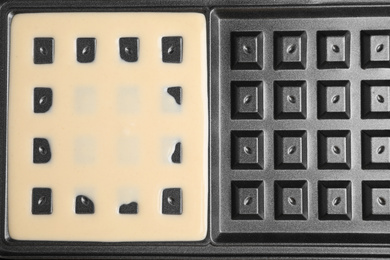Photo of Belgian waffle maker with dough, top view